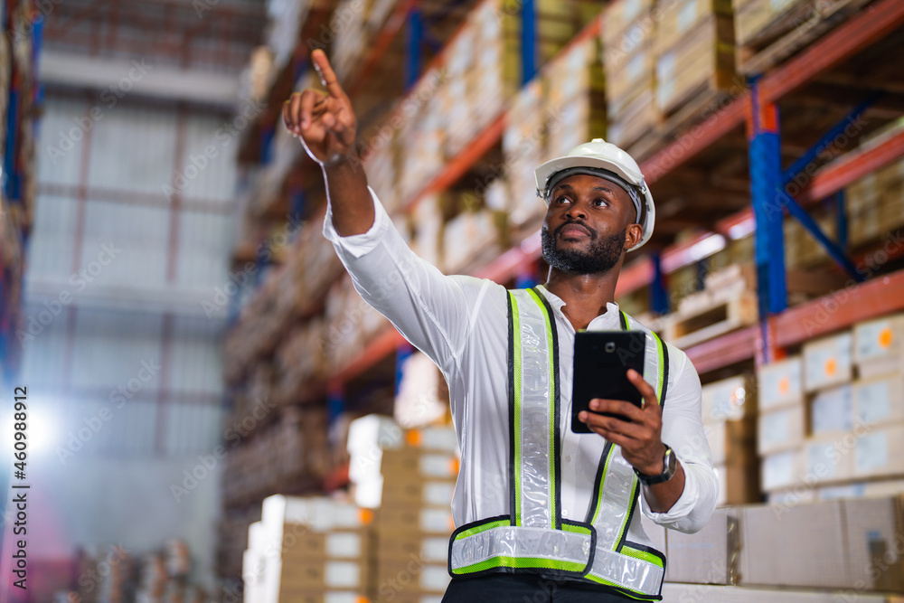 Warehouse worker working process checking the package with a tablet in a large distribution center. 