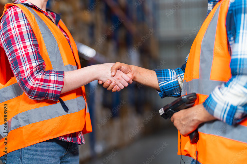 Two warehouse workers shaking hand when success project or first time greeting in a distribution cen