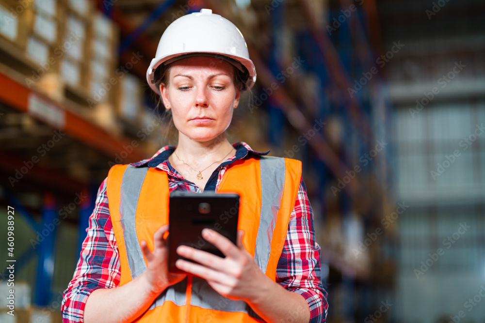 Warehouse worker working process checking the package using a tablet in a large warehouse distributi