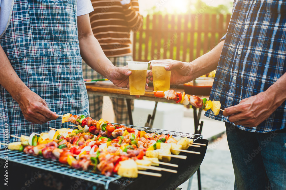 Cheers! Cheers to a group friends drinking beer at an outdoor BBQ party.