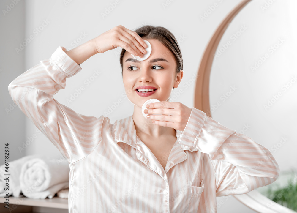 Beautiful young woman removing makeup at home