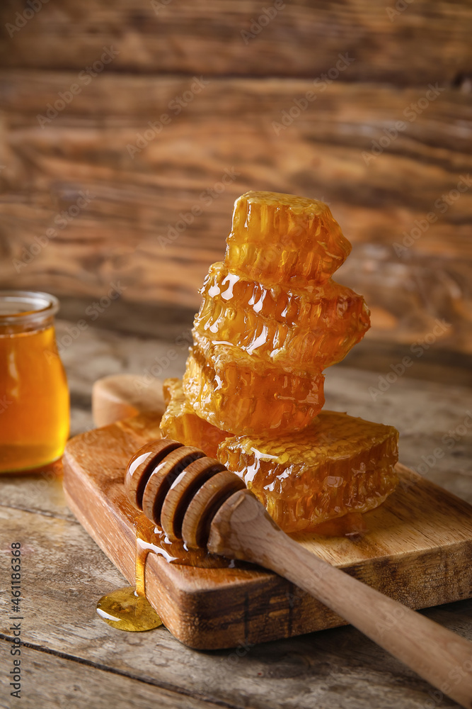 Board with honey combs and dipper on wooden background