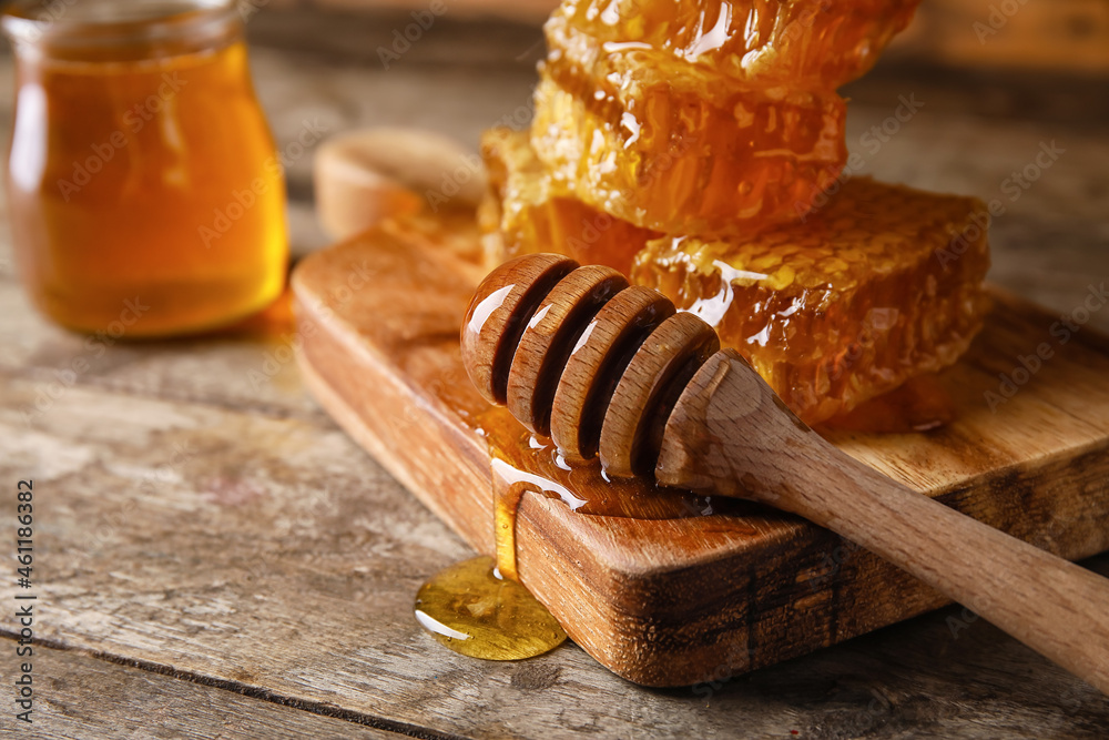 Board with dipper and honey combs on wooden background, closeup