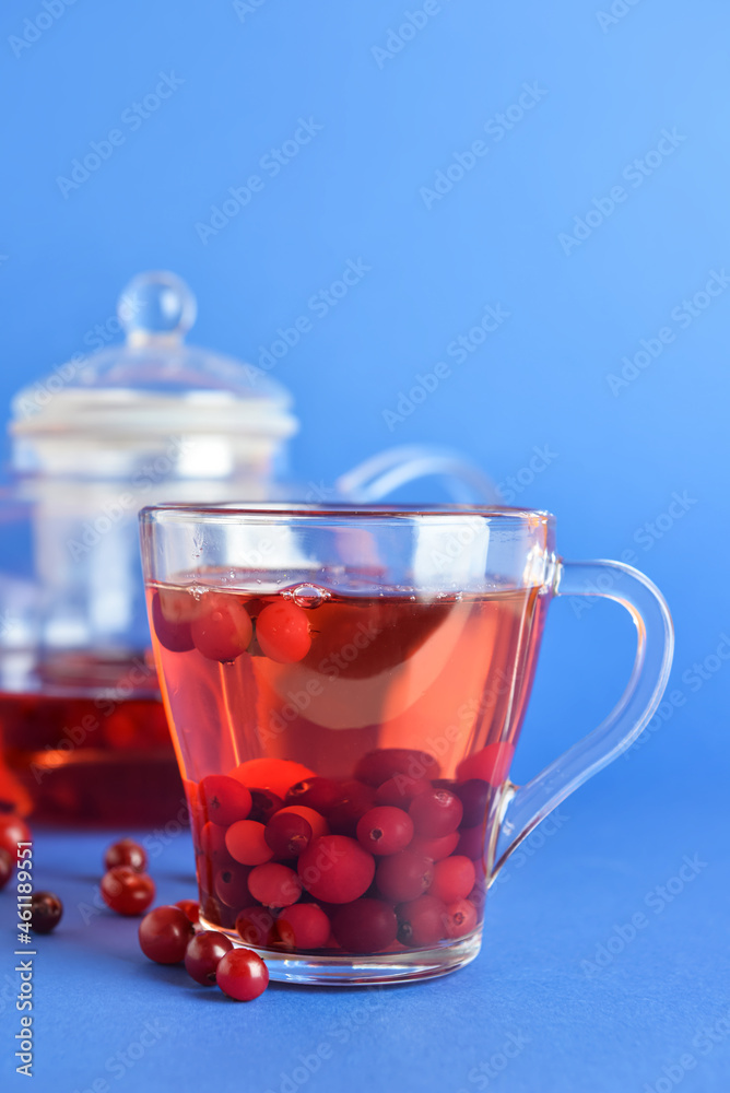 Glass cup of tasty cranberry tea on blue background, closeup