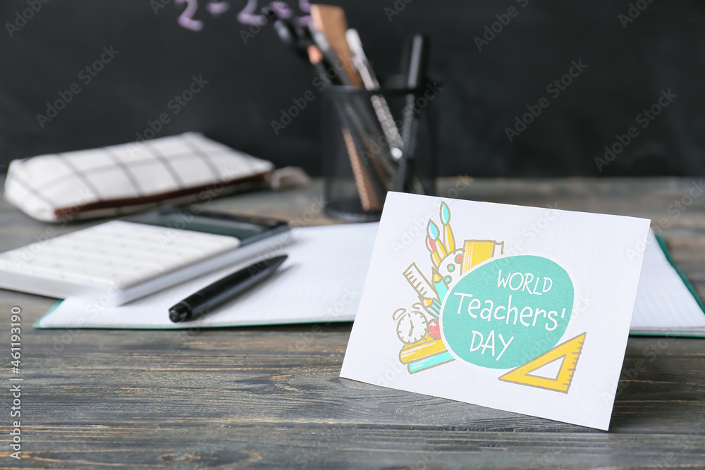 Greeting card for Teachers Day and stationery on wooden table in classroom