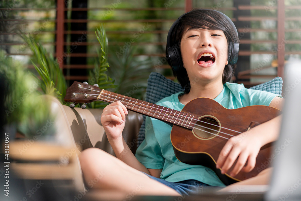 cheerful fun asian child boy singing loud play ukulele with exiting and energy ,asian male son make 