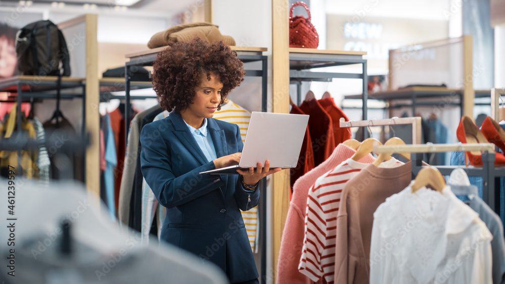 Clothing Store: Female Merchandising Manager Uses Laptop Computer To Create Stylish Fashion Collecti