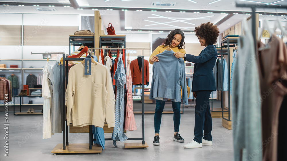 顾客在现代服装店购物，零售助理协助客户。多元化的人i