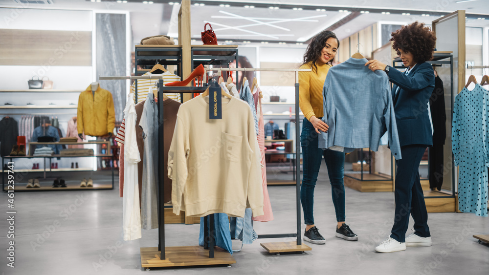 顾客在现代服装店购物，零售助理协助客户。多元化的人i