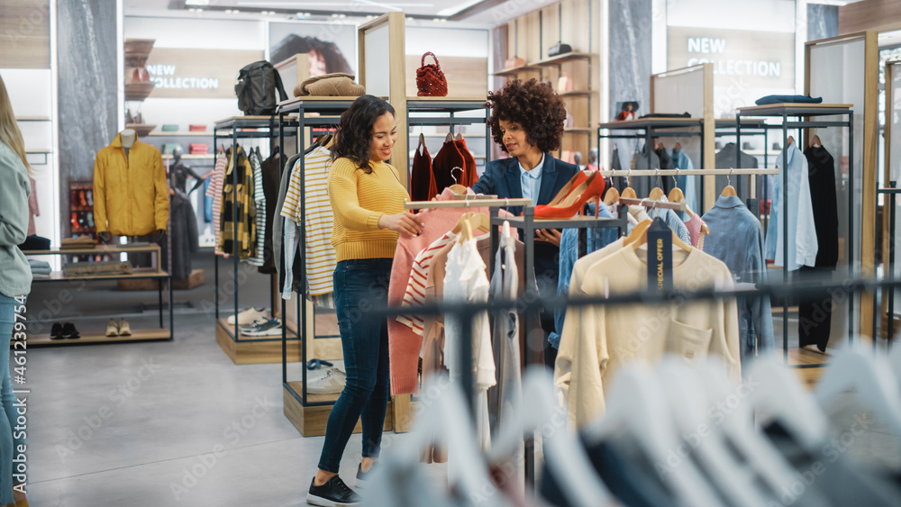 顾客在现代服装店购物，零售助理协助客户。多元化人群i