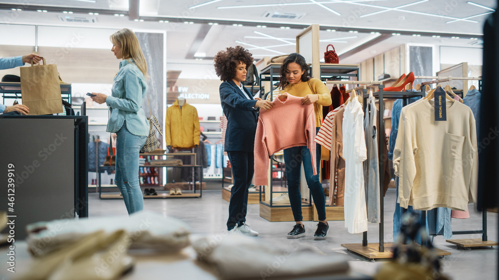 顾客在现代服装店购物，零售助理协助客户。多元化的人i