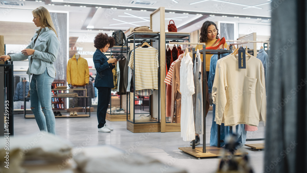 顾客在现代服装店购物，零售助理协助客户。多元化的人i