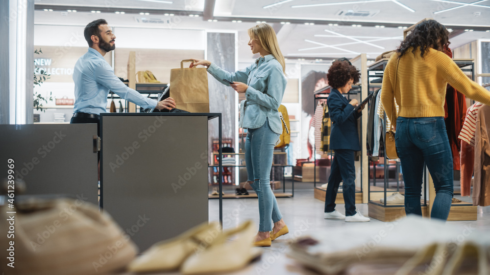 顾客在现代服装店购物，零售助理协助客户。多元化的人i