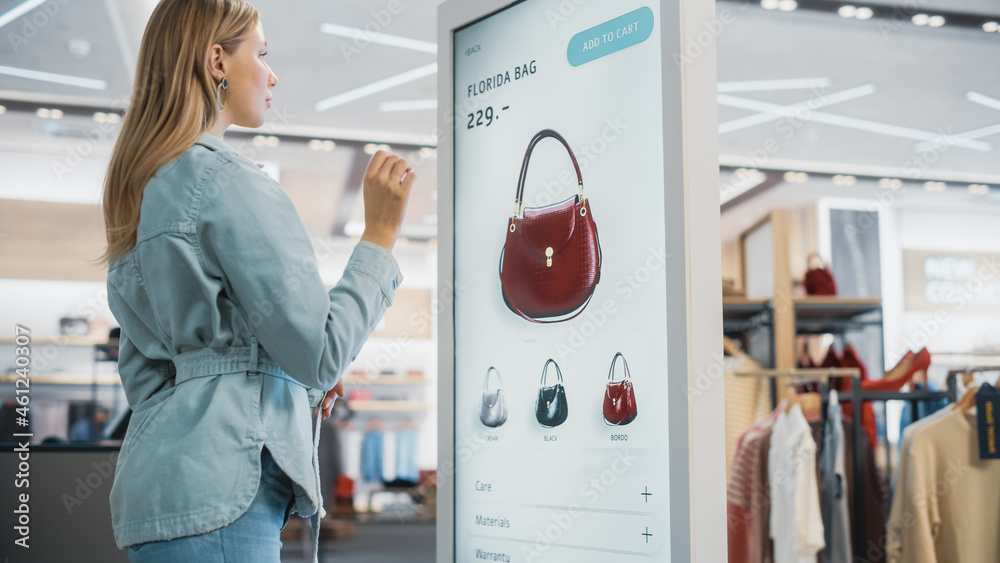 Beautiful Female Customer Using Floor-Standing LCD Touch Display while Shopping in Clothing Store. S