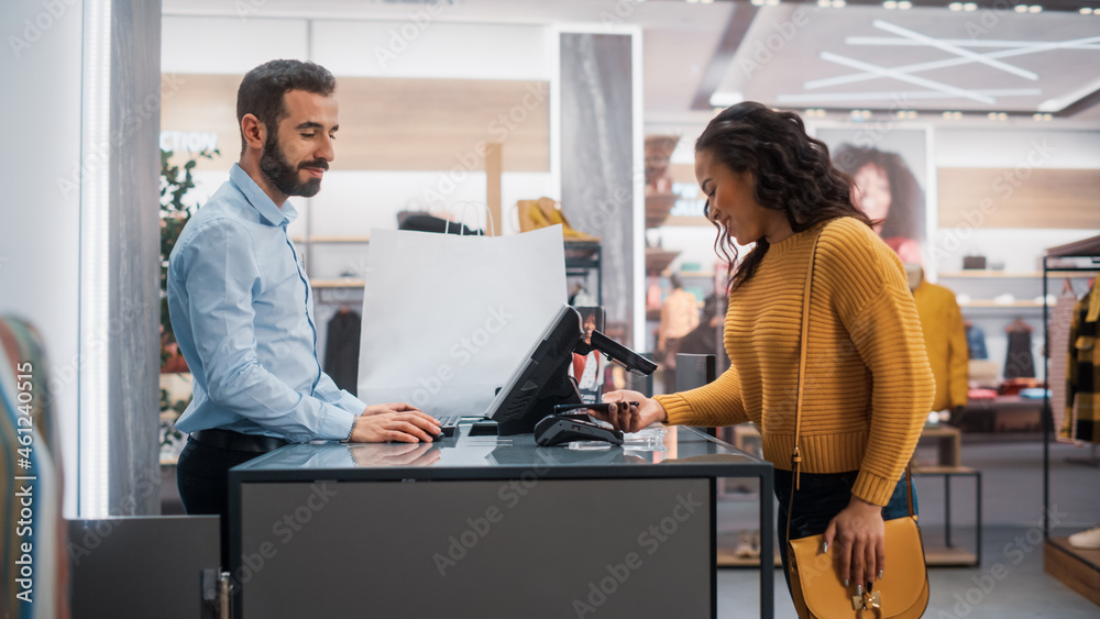 Clothing Store: Young Woman at Counter Buys Clothes from Friendly Retail Sales Assistant, Paying wit