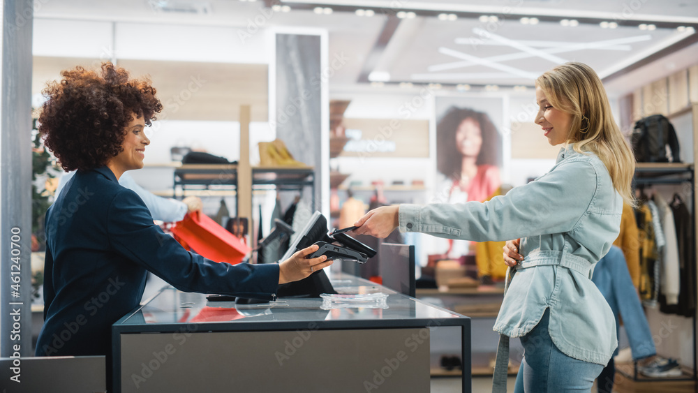 服装店收银台：女性和男性零售销售经理接受NFC智能手机