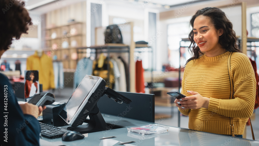 服装店收银台：女性零售销售经理接受NFC智能手机和信用卡