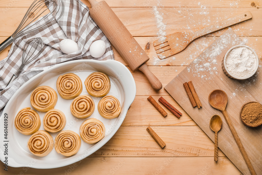 Baking dish with uncooked cinnamon rolls on wooden background