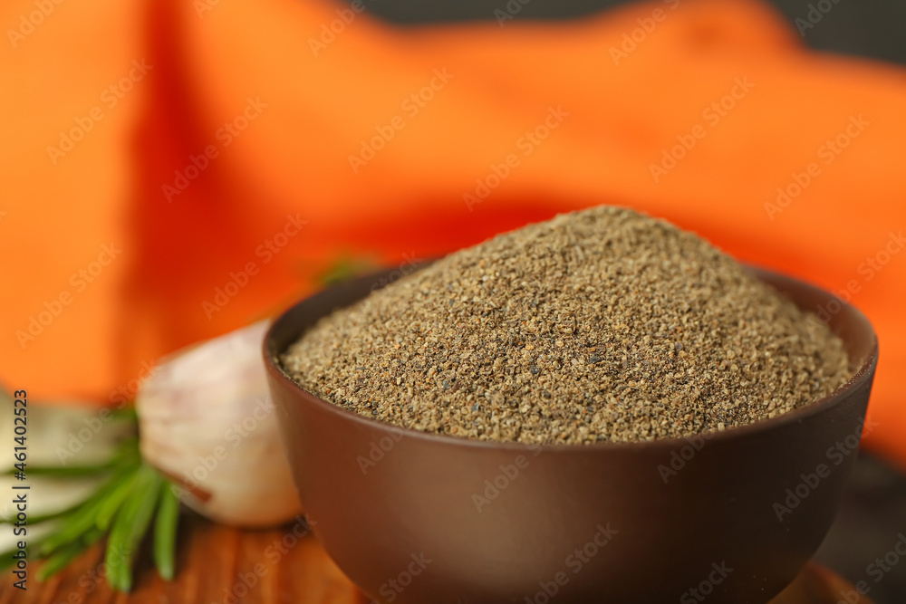 Bowl with black pepper powder on table, closeup