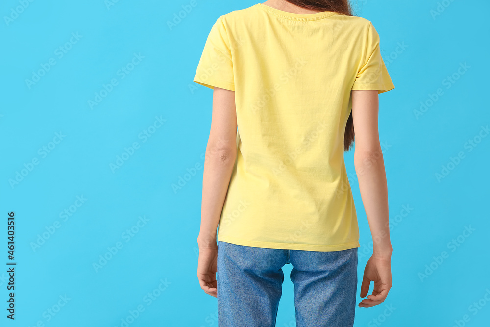 Young woman in modern t-shirt on color background, back view