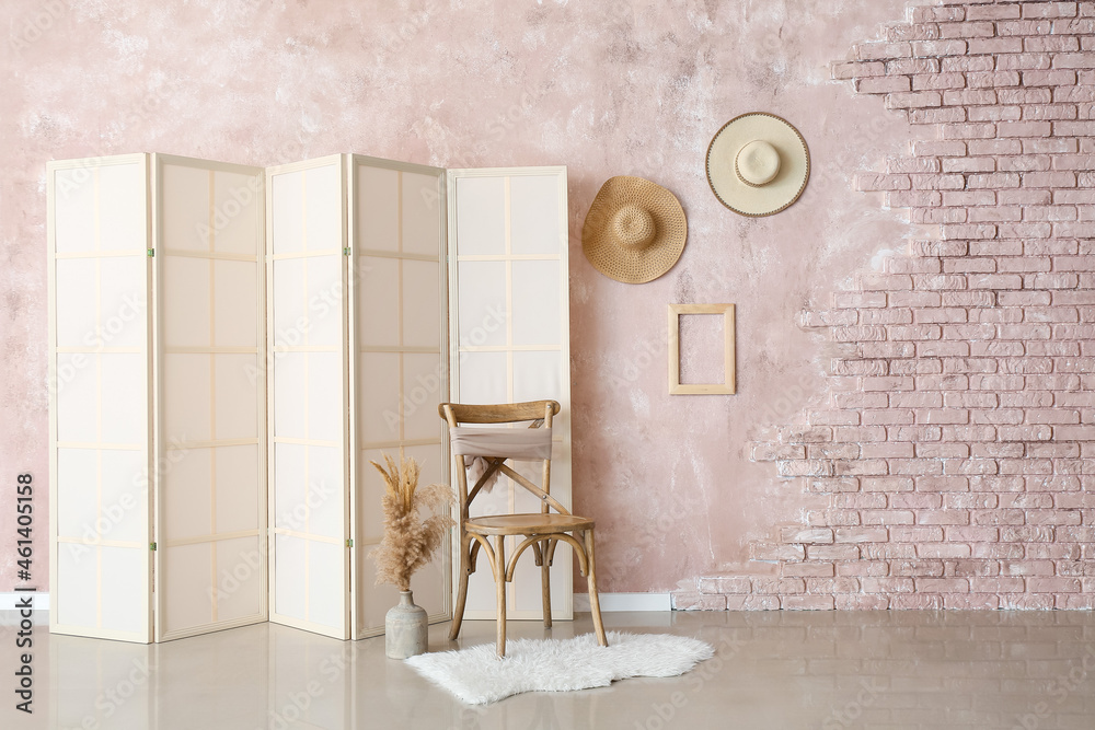 Wooden chair, vase with pampas grass and folding screen near pink wall