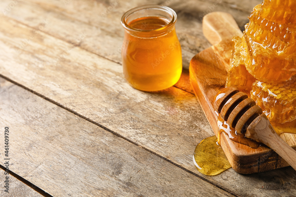 Jar of honey, combs and dipper on wooden background, closeup