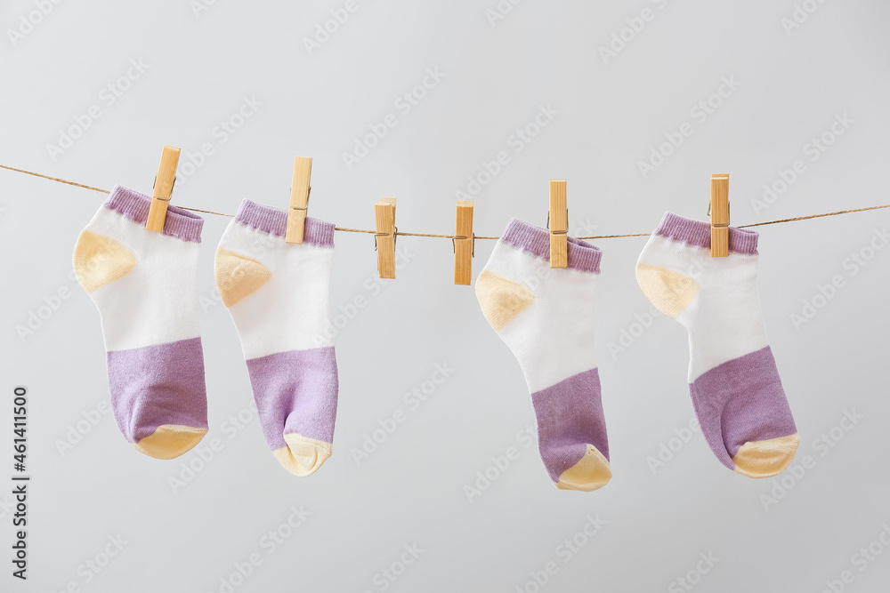 New socks hanging on rope against grey background