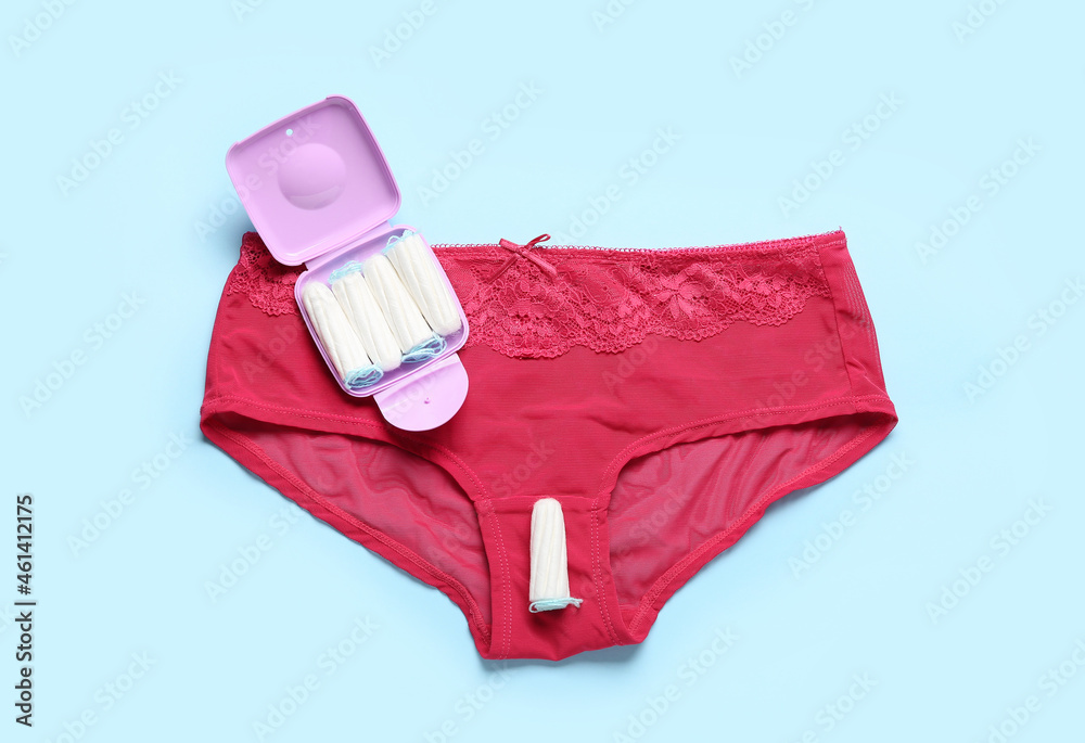 Tampons storage box and female panties on blue background, top view