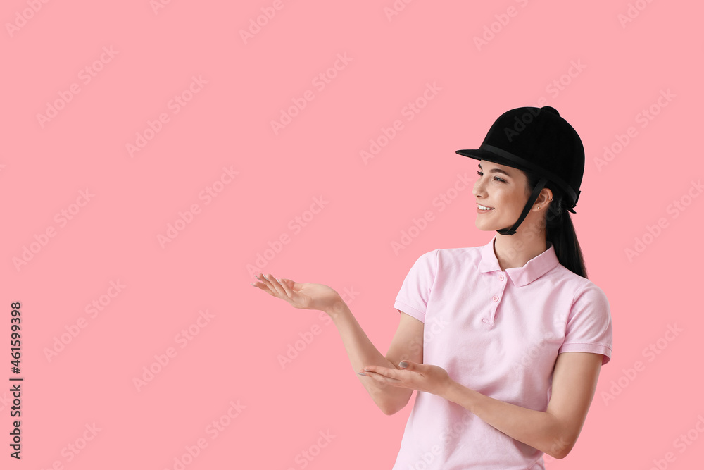 Beautiful female jockey showing something on color background