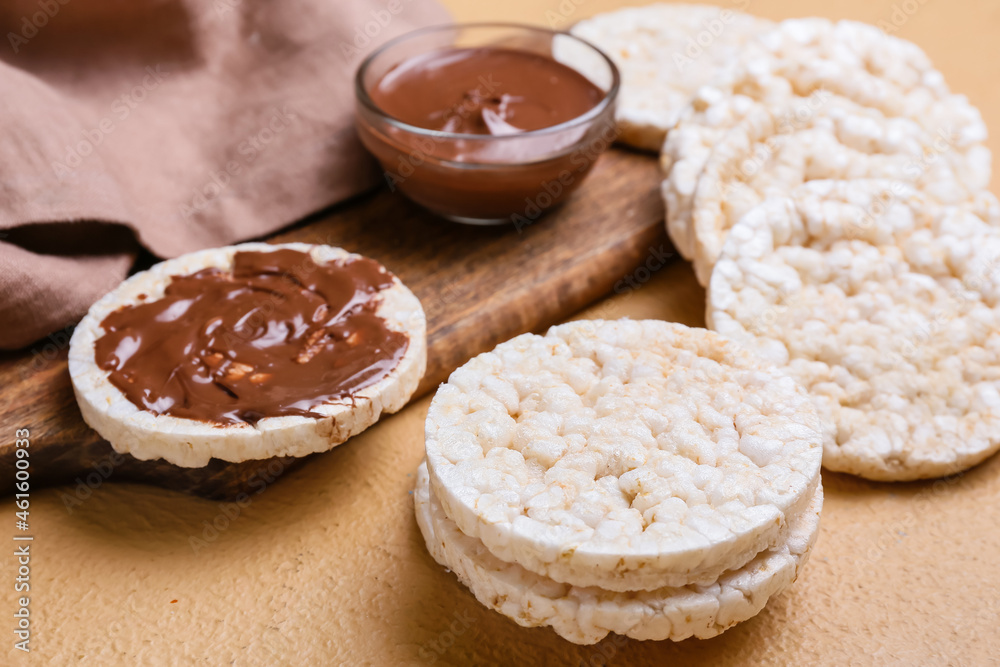 Puffed rice crackers and melted chocolate on color background, closeup