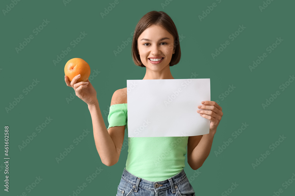 Young woman with grapefruit and blank poster on color background. Vegan Day