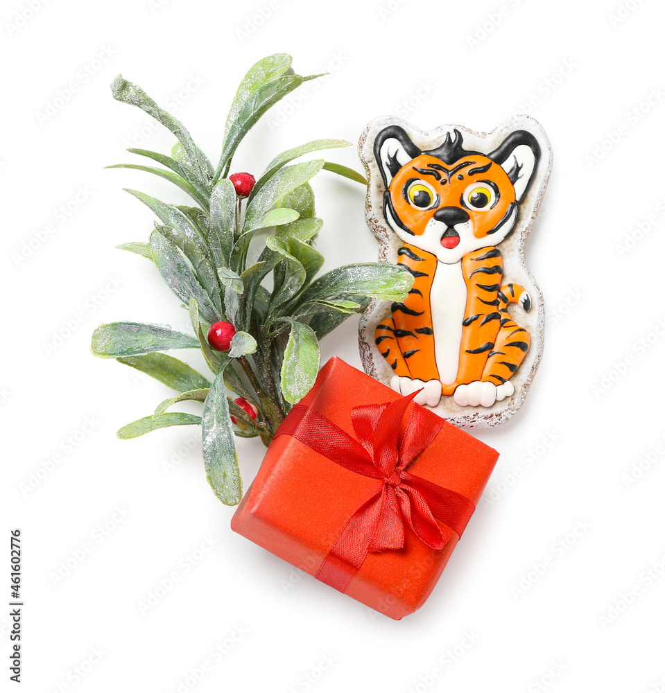 Cute cookie in shape of tiger, mistletoe and New Year gift on white background