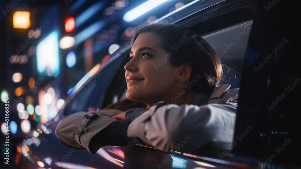 Excited Young Female is Sitting on Backseat of a Car, Commuting Home at Night. Looking Out of the Wi