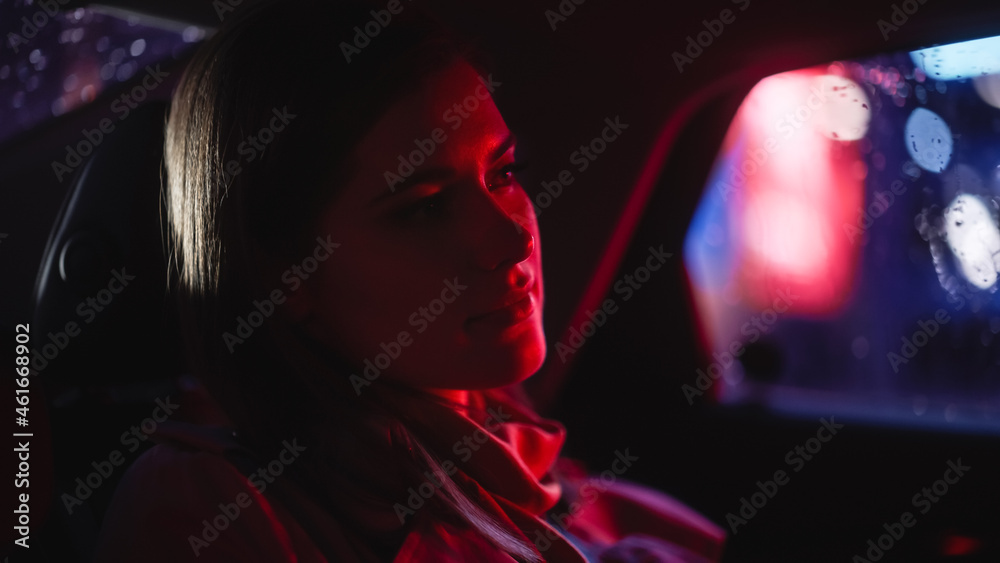 Close Up Portrait of a Female Commuting Home in a Backseat of a Taxi at Night. Beautiful Woman Passe