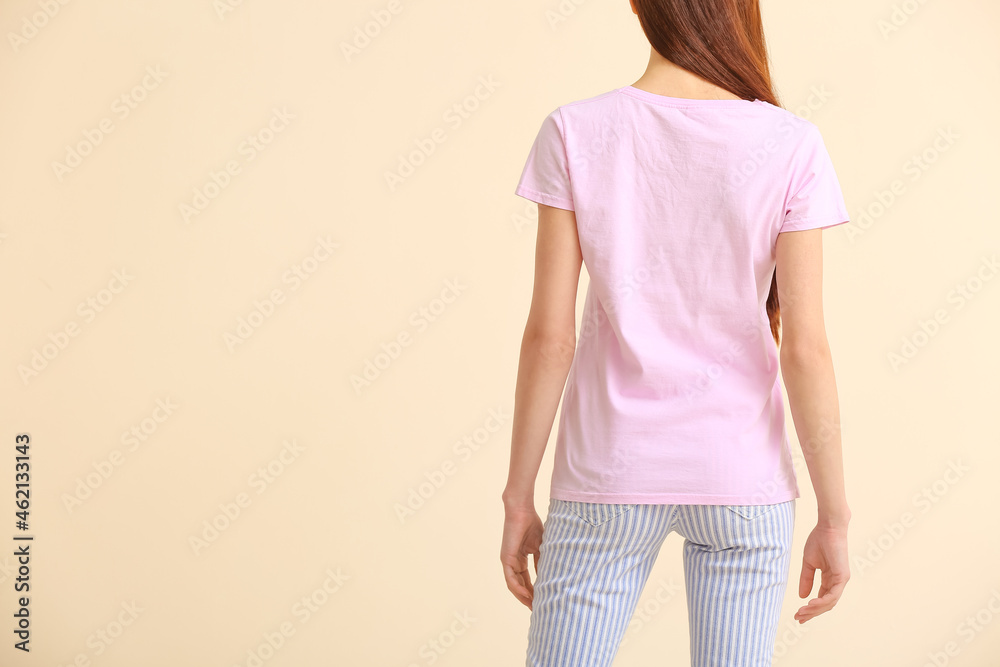 Young woman in modern t-shirt on color background, back view