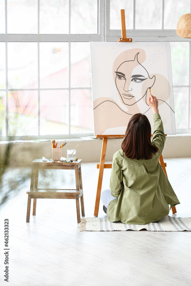 Young female artist painting in workshop