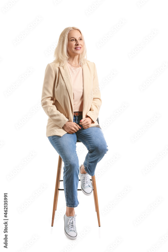 Beautiful mature woman sitting in chair on white background