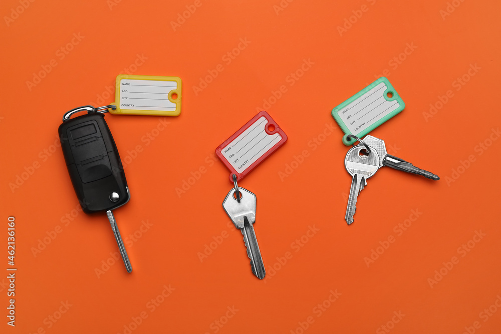 Different keys with plastic tags on orange background