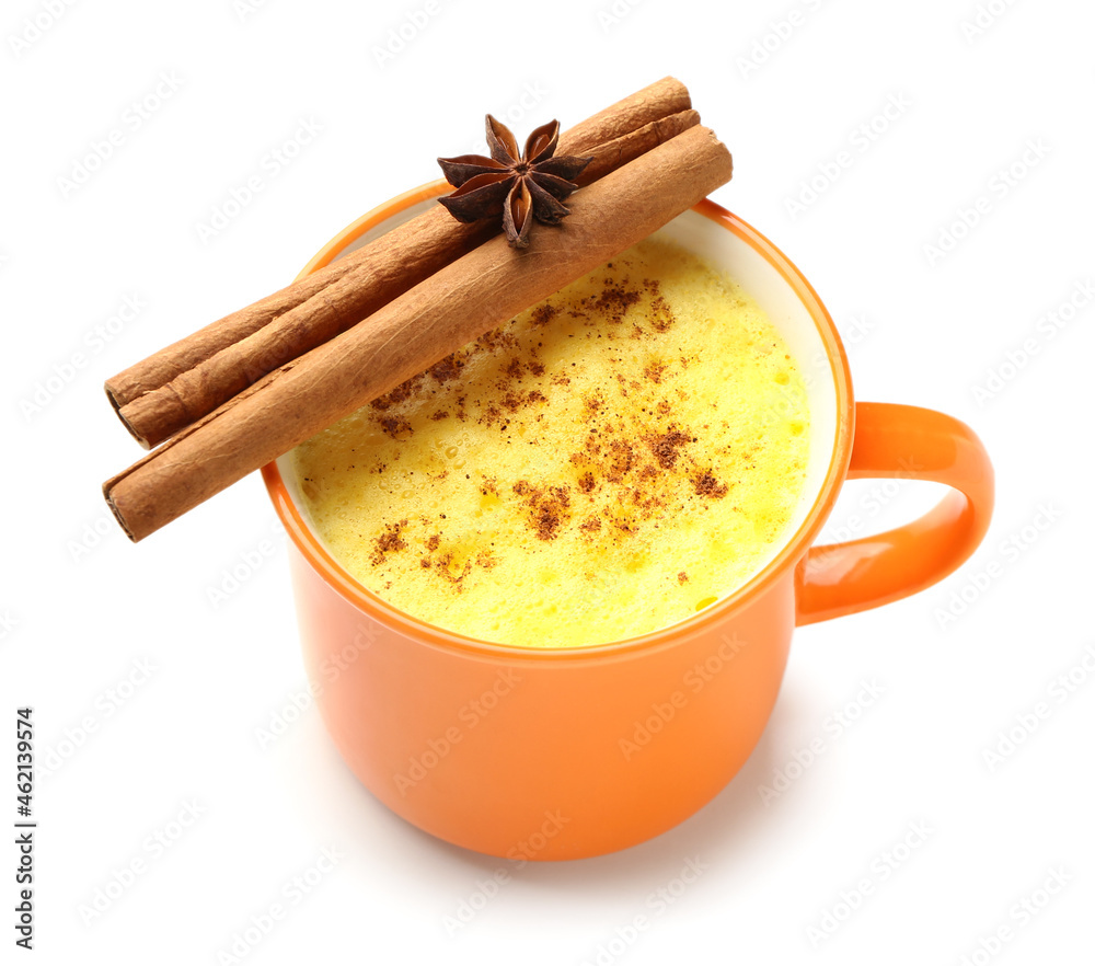 Cup of healthy turmeric latte with star anise and cinnamon on white background