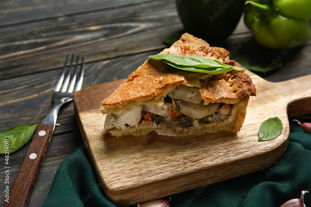 Board with piece of tasty chicken pot pie on dark wooden background