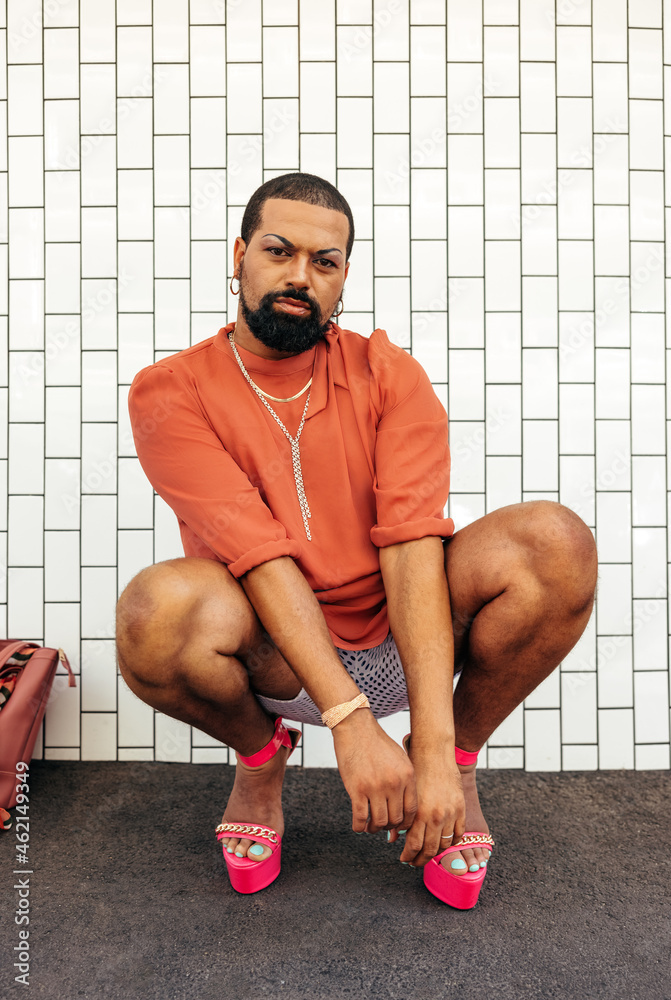 Young drag queen squatting against a white background