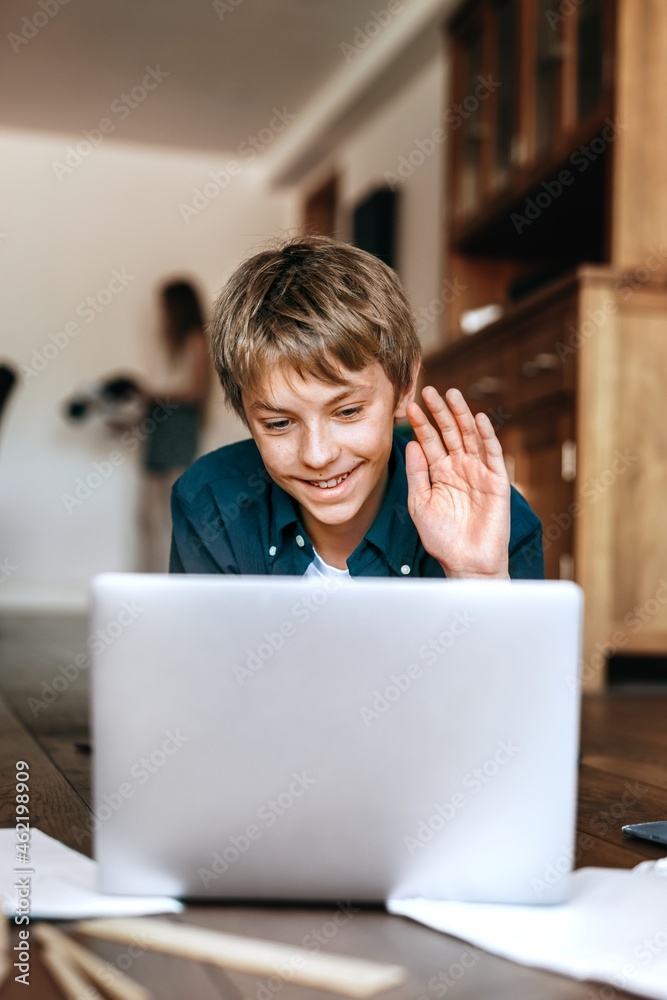 Boy using laptop on wooden floor, the new normal