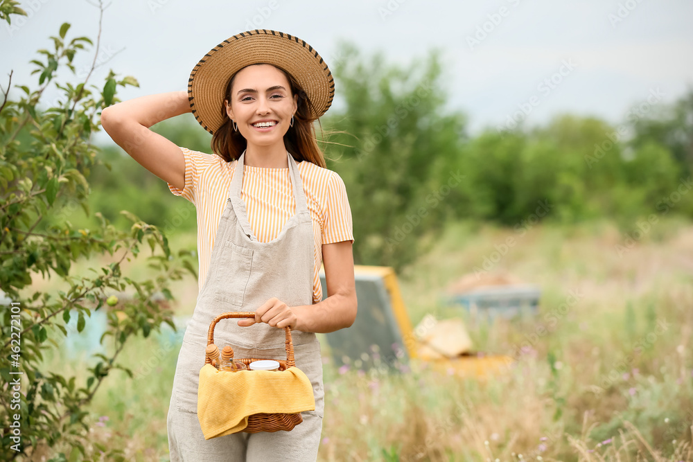 Female beekeeper with honey at apiary