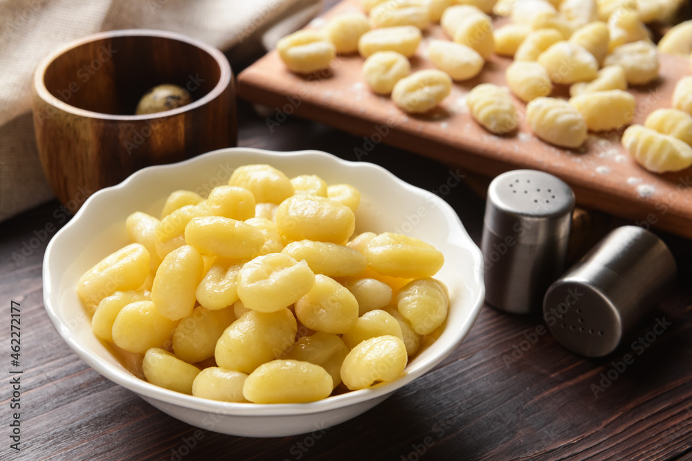 Bowl with tasty gnocchi on wooden background