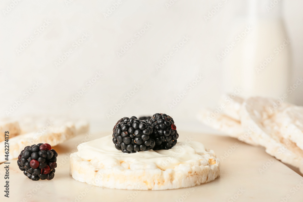 Puffed rice cracker with blackberry on light background, closeup