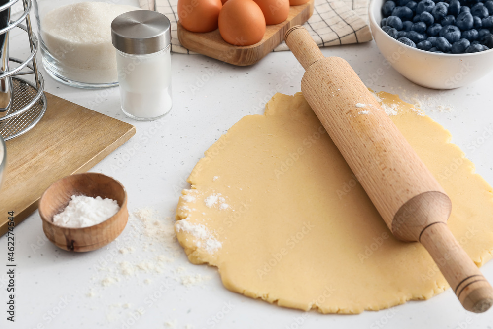 Raw dough with ingredients for blueberry galette on light background, closeup