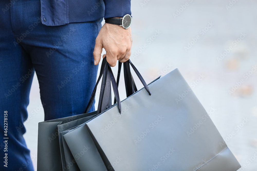 Young man with shopping bags on city street, closeup