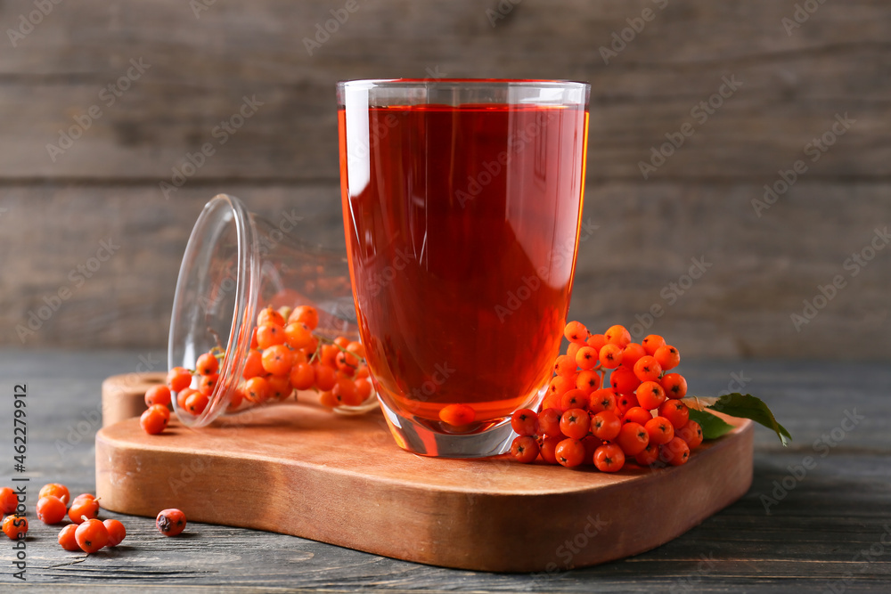 Glass of tasty rowan tea and berries on wooden background