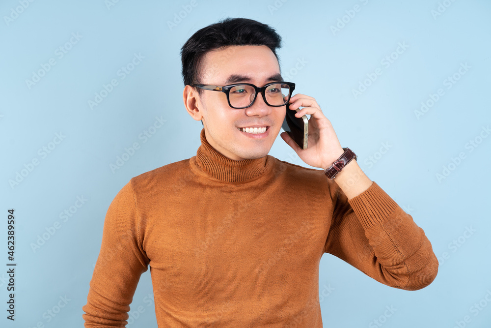 Asian man using smartphone on blue background