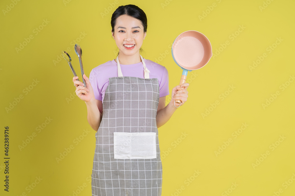 Young Asian housewife posing on yellow background